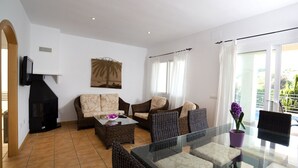 A living room with a sofa, two armchairs, a glass-top table, a fireplace, and a balcony with curtains. - Beautiful  villa for 6 people with WIFI, private pool, TV, terrace and panoramic view (Calpe)