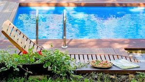 A wooden deck with a pool, a lounge chair, and a table with a plate of food and a magazine. - Wonderful private villa with WIFI, private pool, hot tub, A/C, TV, patio and pets allowed (Rijeka)