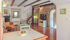 A cozy living room with a fireplace, a television, and a dining area with a stone wall. - Wonderful private villa with WIFI, private pool, hot tub, A/C, TV, patio and pets allowed (Rijeka)