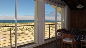 A room with a view of the beach, a dining table with chairs, and a ceiling fan. - Nice apartment for 4 guests with WIFI, TV and balcony (Mimizan)