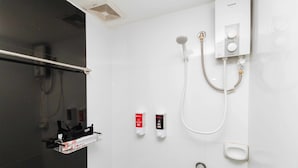 A modern bathroom with a glass shower enclosure, a handheld showerhead, a wall-mounted control panel, and two soap dispensers. - RedDoorz near Bambang Station (Manila)