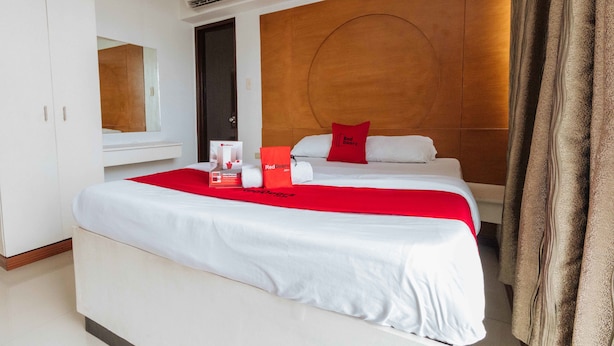 A hotel room with a large bed, a wooden headboard, a mirror, and a wardrobe. - RedDoorz near Bambang Station (Manila)