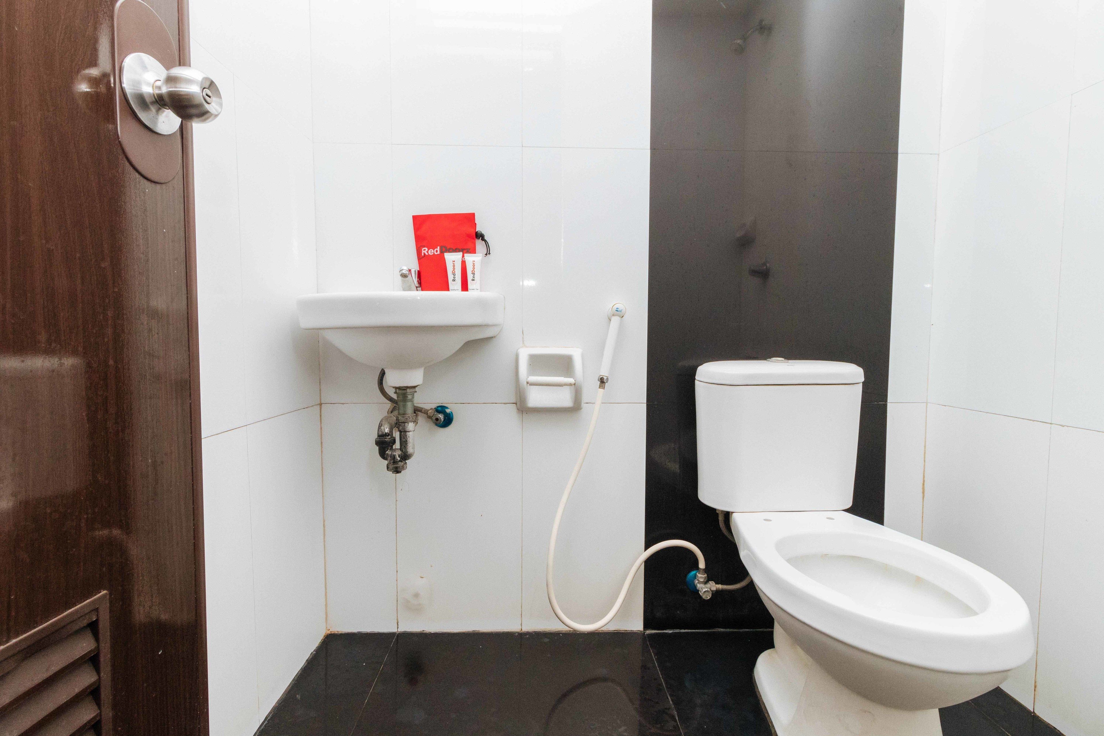 A bathroom with a toilet, sink, and a red box on the wall.