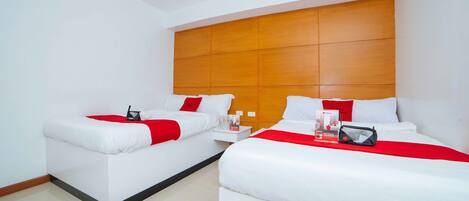 A hotel room with two beds, a wooden headboard, white bedding, and a red accent.