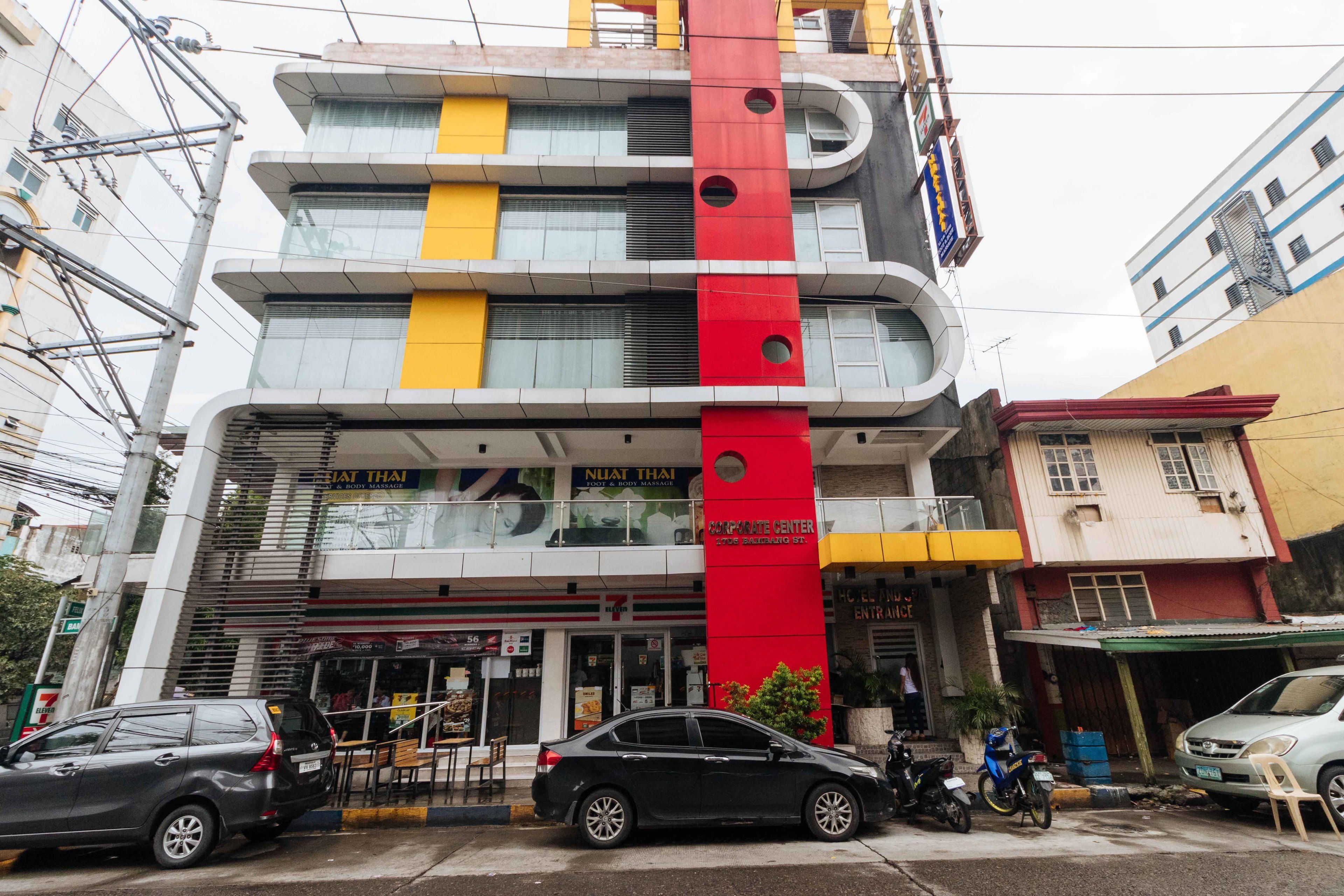 A multi-story building with a prominent red vertical stripe, a ground-level entrance, and a visible restaurant named "Nuat Thai" on the ground floor.