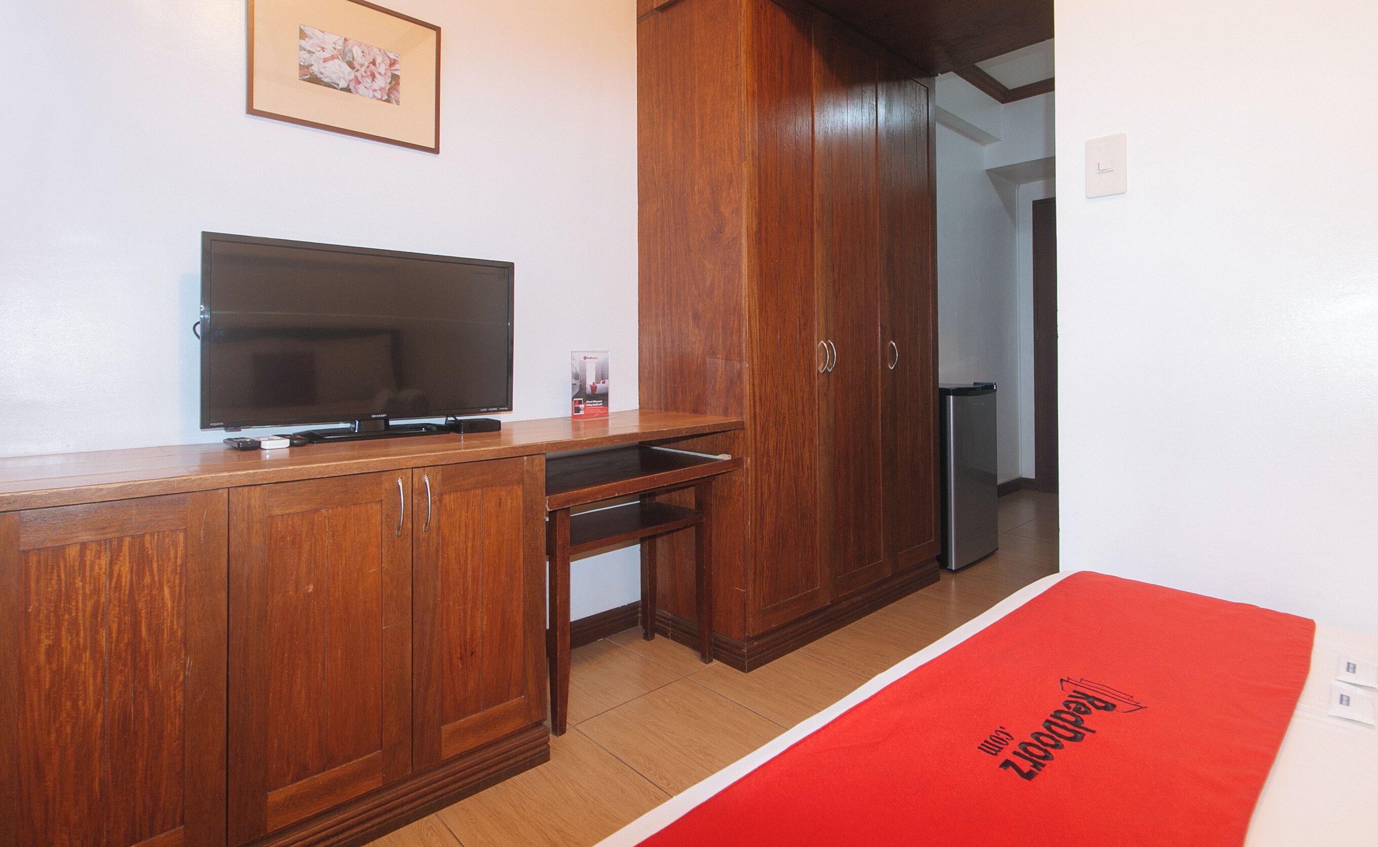 Une pièce avec un meuble en bois, un téléviseur à écran plat et un tapis rouge orné de motifs.