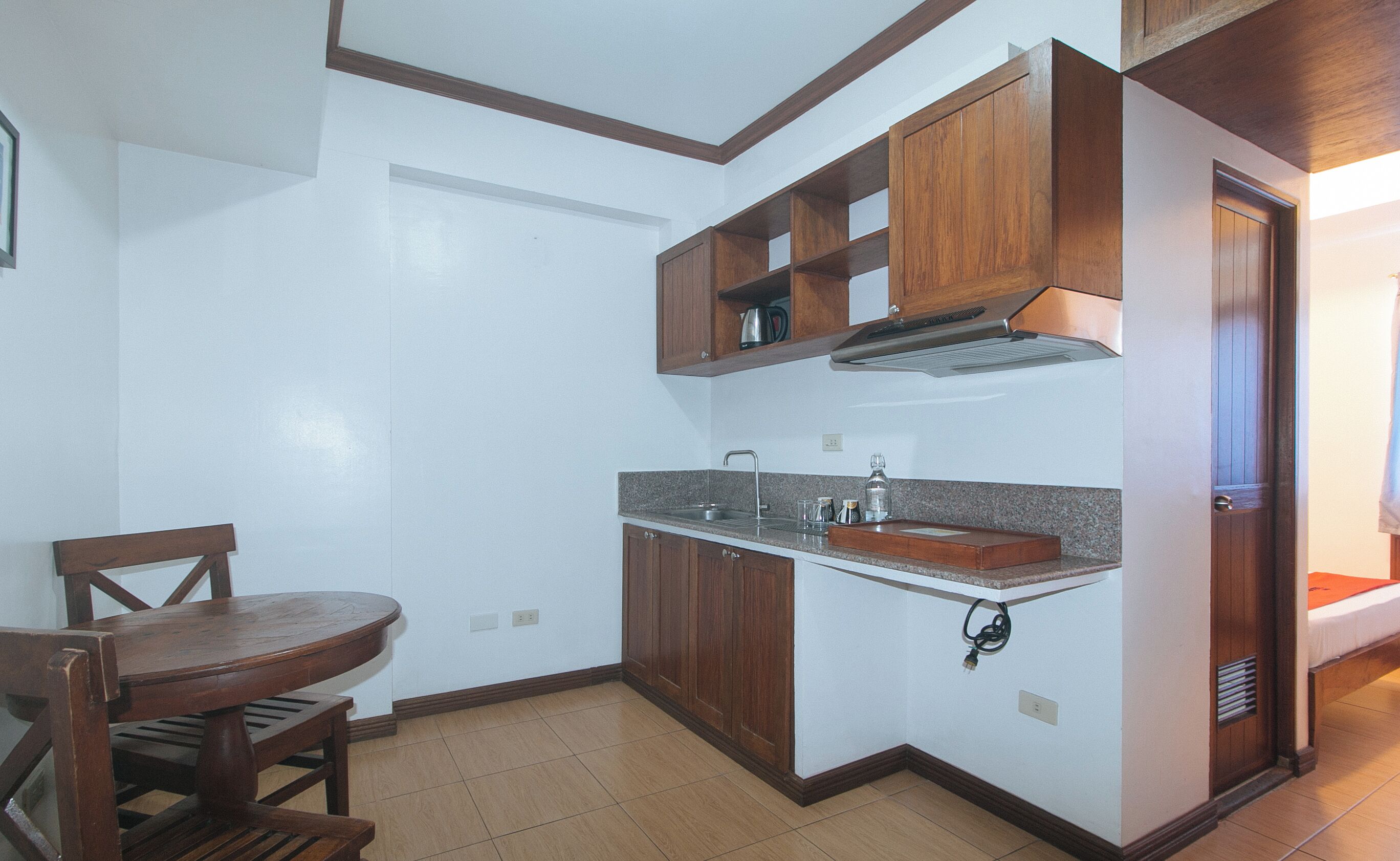 Une cuisine de taille réduite, avec des meubles de rangement en bois, un évier et une table à manger.