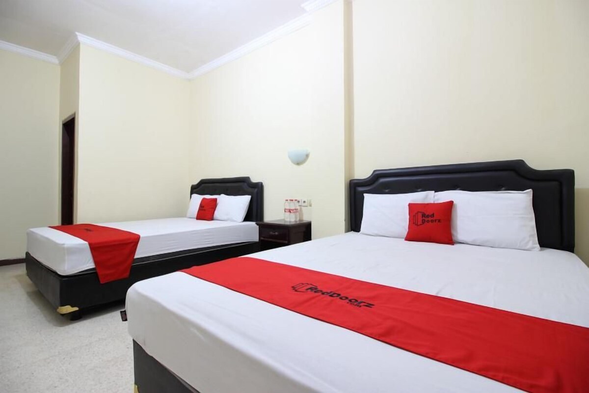 A hotel room with two beds, each with a red and white bedspread and matching pillows.