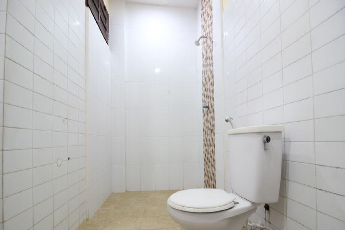 A small, white-walled bathroom with a toilet and shower.