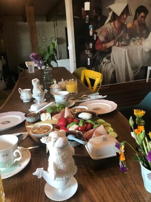 Ein Esstisch mit verschiedenen Speisen, darunter Früchte, Käse und eine Teekanne.