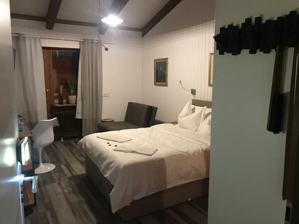 Ein Hotelzimmer mit einem Bett, einem Sessel, einem kleinen Tisch und einer Topfpflanze.