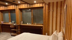 A wooden-paneled room with a bed, a desk, and two windows. - Steinacher Hof (Fuerth)