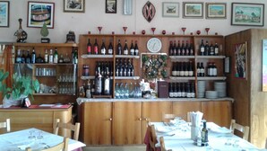 A restaurant with wooden shelves stocked with wine bottles, a clock, and various framed artworks on the walls. - Hotel Conca D'Oro (Lama Mocogno)