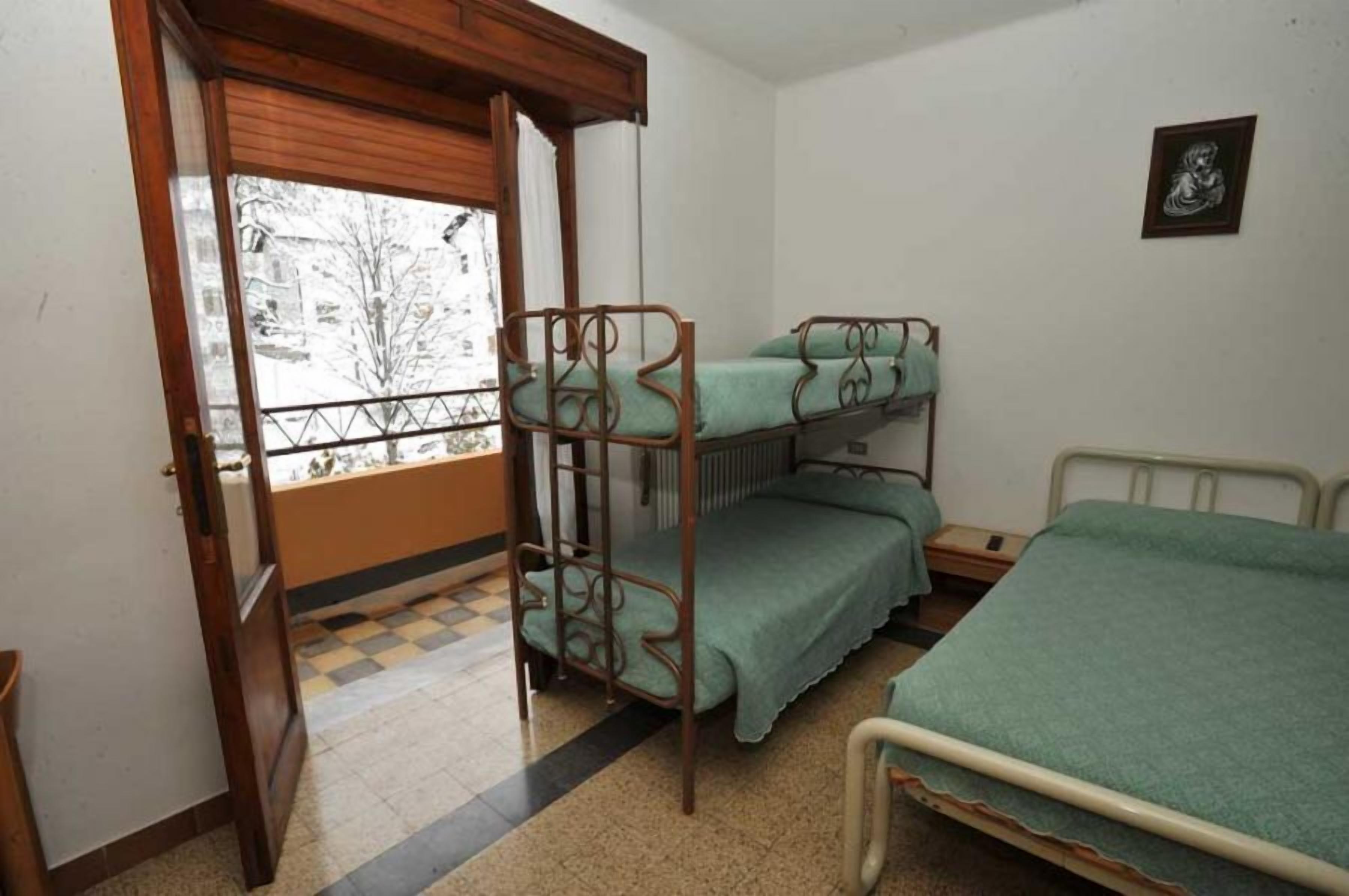 Una habitación con literas, una ventana que da a un paisaje nevado y un piso a cuadros.