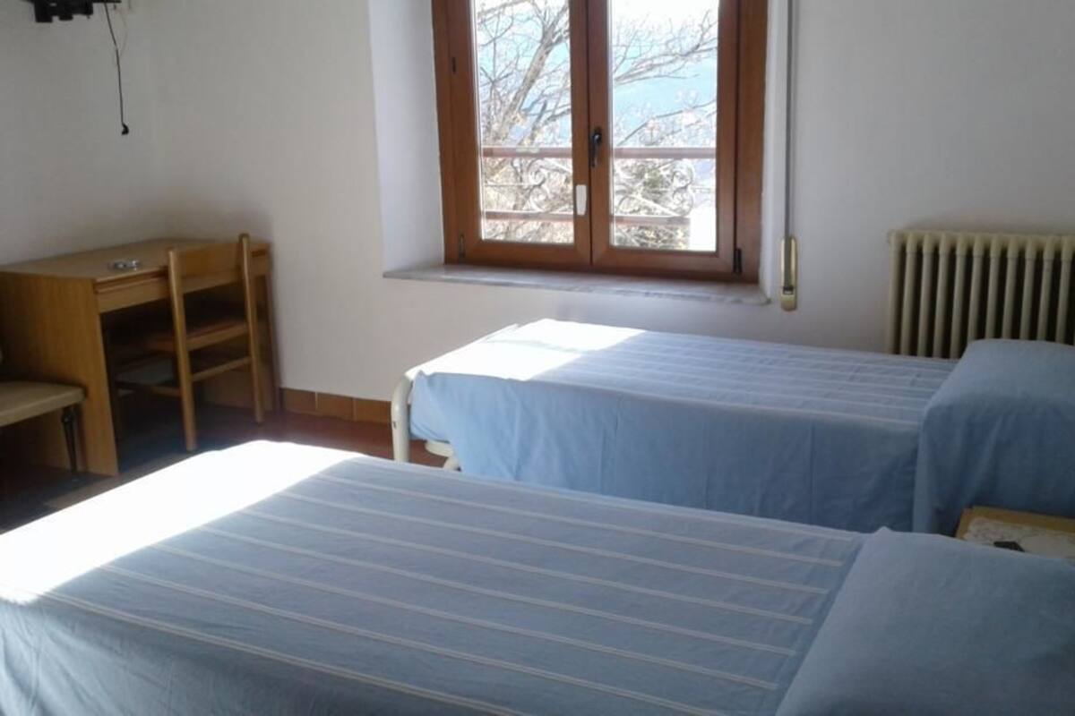 A room with two beds, a desk, and a window.