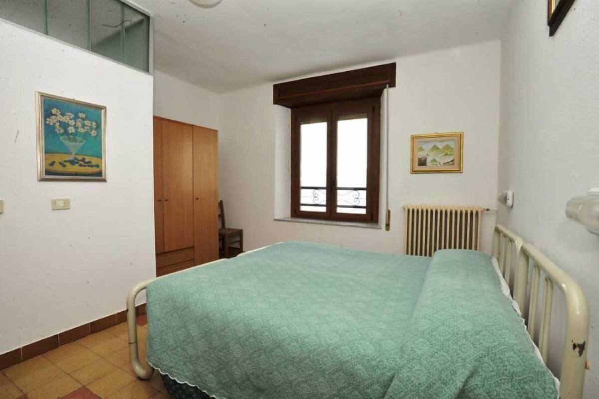 A bedroom with a single bed, a window, a radiator, and a door.
