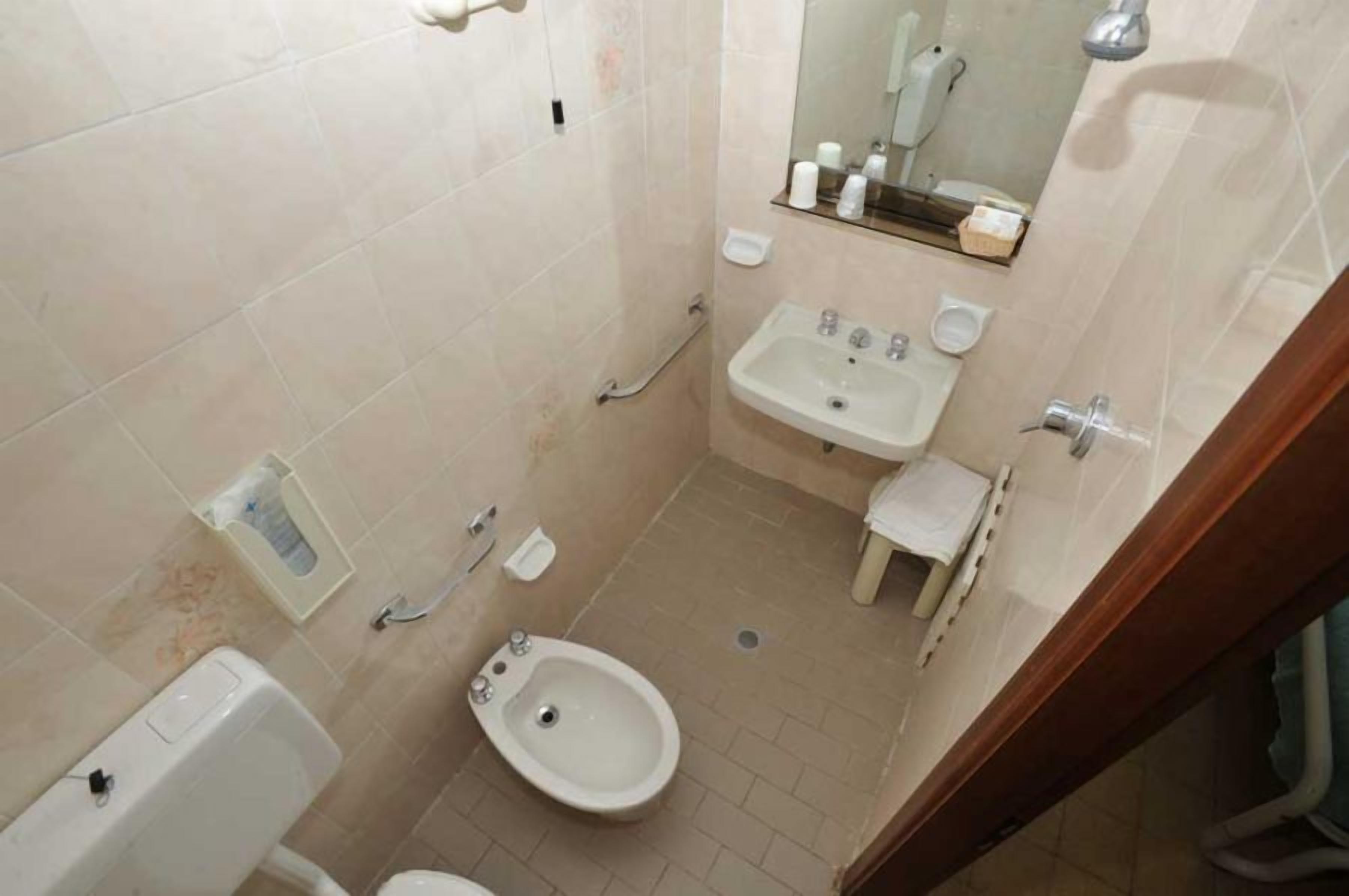 Une petite salle de bain compacte comprenant des toilettes, un bidet, un lavabo et un miroir.
