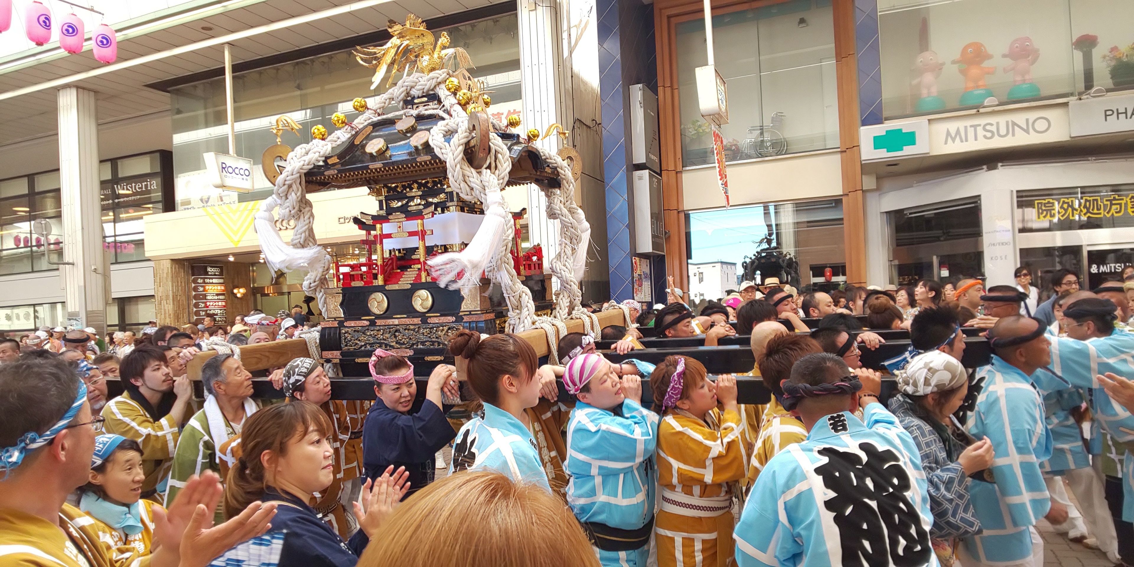 A crowded indoor event with a central display featuring a decorated structure.