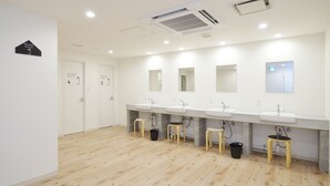 A modern bathroom with three sinks, wooden stools, and a sign indicating the shower room. - Otaru YaDo - Hostel (Otaru)