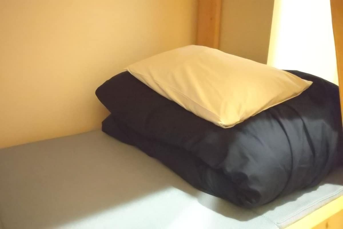 A small, enclosed sleeping area with a single bed, a pillow, and a wooden headboard.