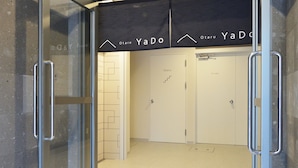 A hotel entrance with a glass door, a sign above the door, and a tiled floor. - Otaru YaDo - Hostel (Otaru)