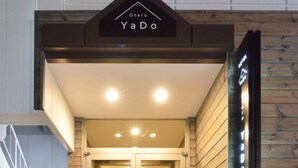 A hotel entrance with a sign reading "Otaru YaDo," a staircase leading up to the doors, and a wooden wall to the right. - Otaru YaDo - Hostel (Otaru)
