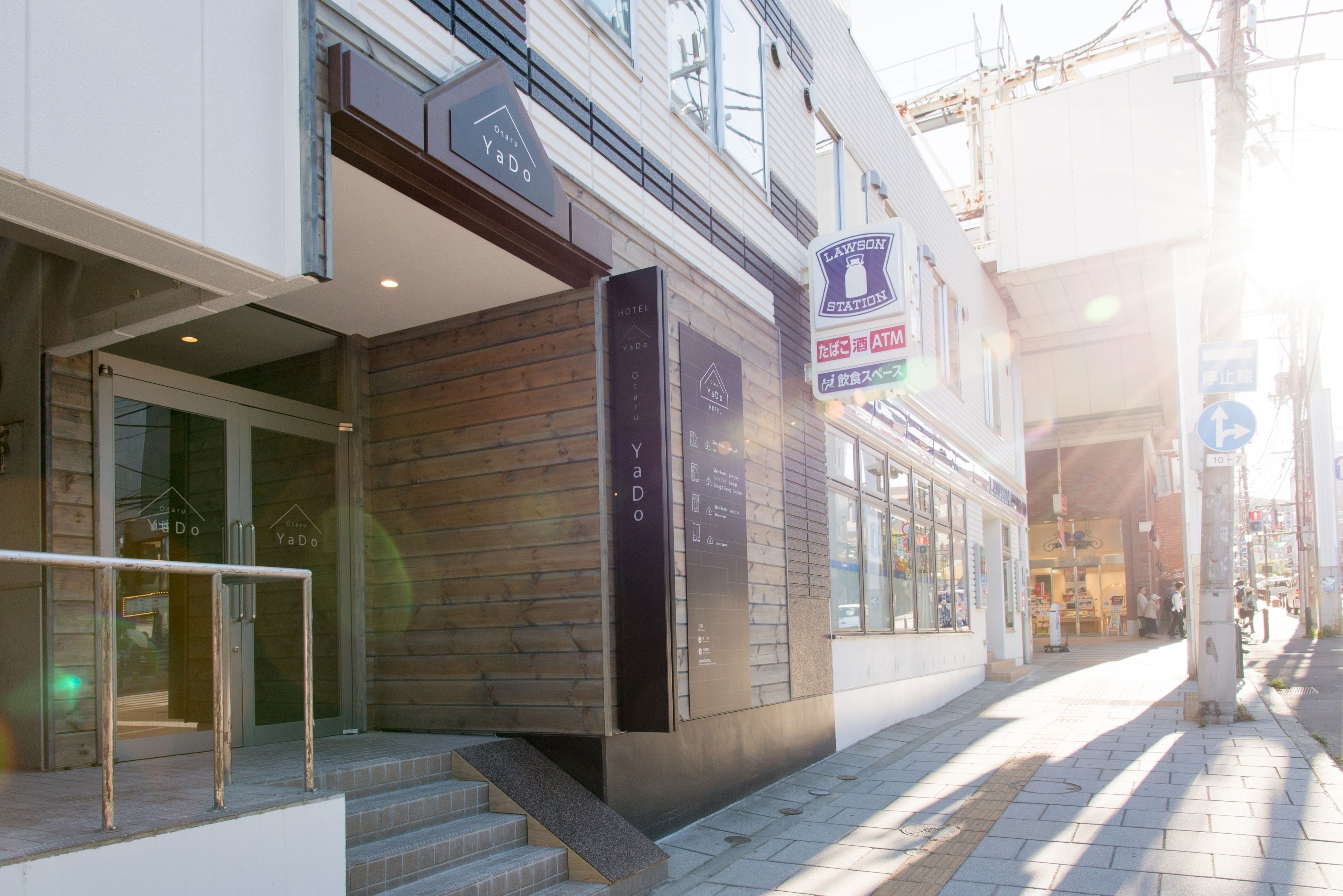 A hotel entrance with a wooden facade, a staircase leading to the entrance, and a sign indicating an ATM.