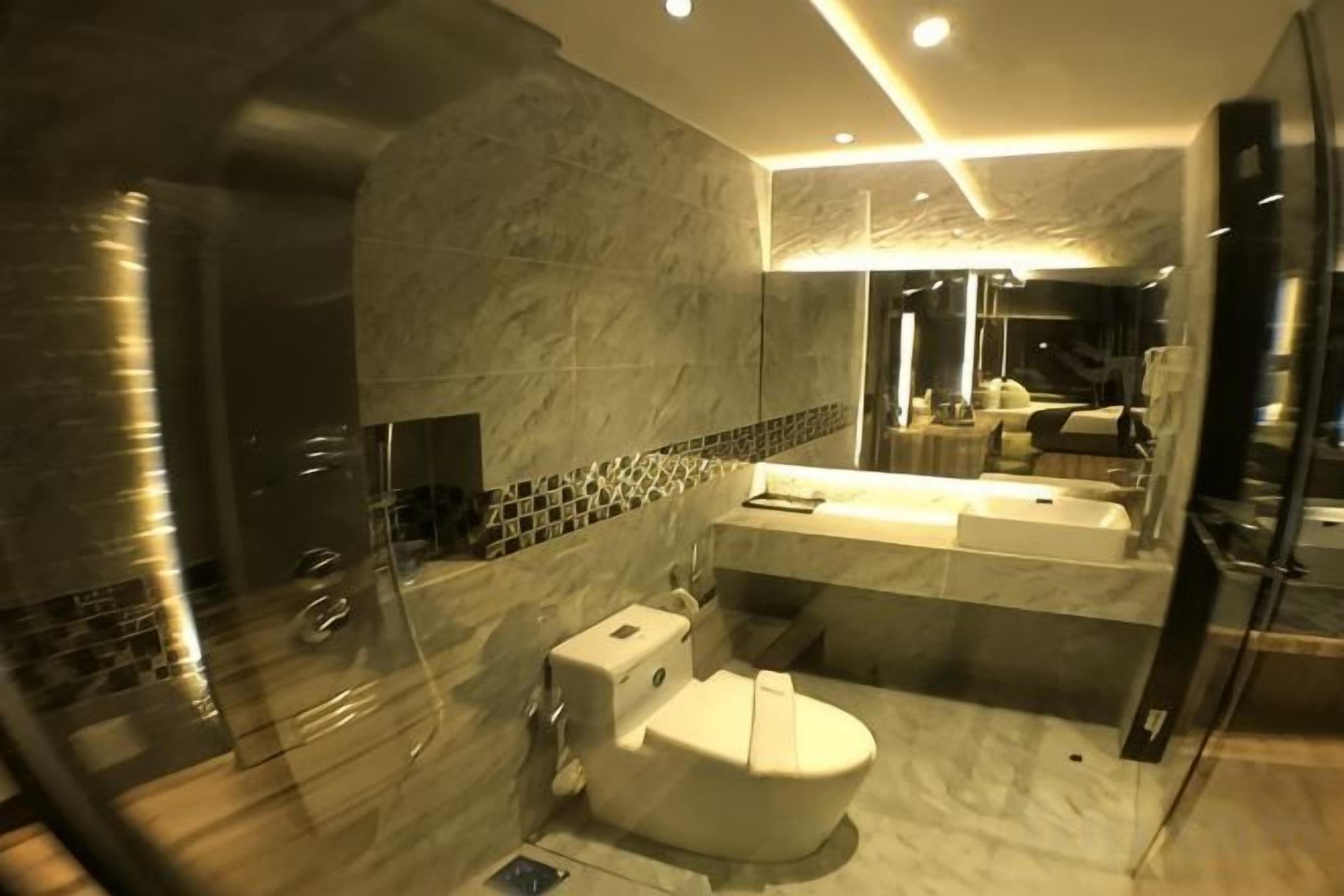 Une salle de bain moderne avec une douche à parois de verre, un lavabo en marbre et des toilettes.