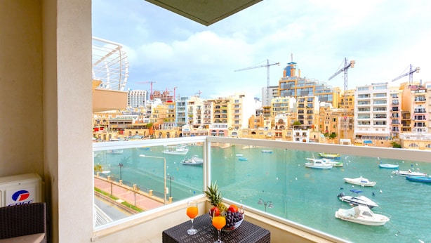 Un balcón con vistas a un puerto deportivo, una mesa con bebidas y un refrigerador de Pepsi.
