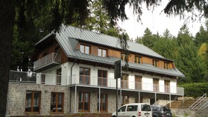 A two-story building with a stone facade, wooden balconies, and a car parked in front.