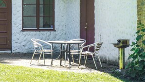 An outdoor patio with a round table and four chairs, a potted plant, and a metal grill. - 3 bedroom cozy home in Tomelilla (Tomelilla)