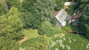 A rural house with a sloped roof, surrounded by dense greenery and a small stream. - 3 bedroom cozy home in Tomelilla (Tomelilla)