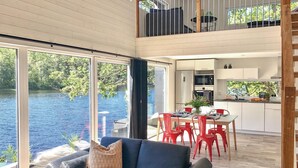 Un interior modern amb zona de menjador, cuina i vista a un llac.