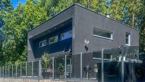Un edifici modern de dos pisos amb exterior fosc, finestres grans i façana de pedra.