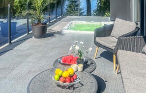 A modern outdoor seating area with a hot tub, a glass balustrade, and a potted plant. - Gorgeous home in Borås with sauna (Borås)