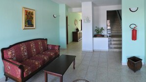 A living room with a sofa and a coffee table, a staircase, and a fire extinguisher on the wall. - Hotel Pietrapanna (Calvello)