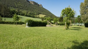 Un campo cubierto de hierba con un parque infantil y una montaña al fondo.