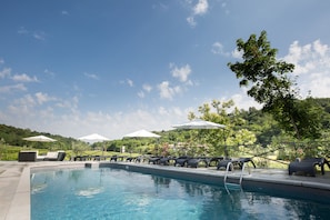 Una piscina al aire libre de temporada, sombrillas, tumbonas