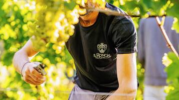 En person i en sort t-shirt med logo og tekst, der holder en kniv og en smartphone.
