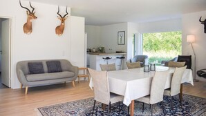 Een moderne woonkamer met een eethoek, een bank en twee opgezette antilopekoppen aan de muur.
