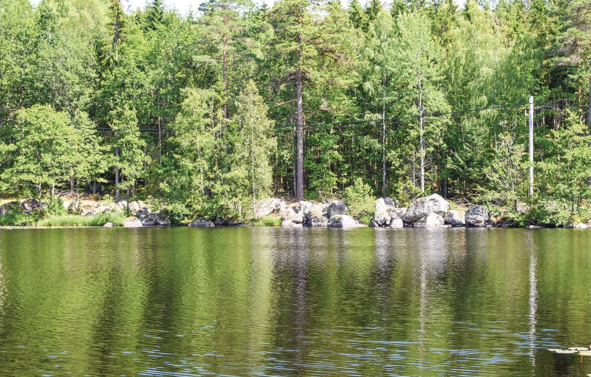 Un llac tranquil envoltat de bosc dens, amb roques grans al voltant de la riba.