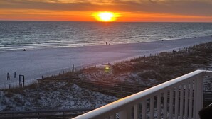 Ein Strand mit Sonnenuntergang, einer Holzlattenveranda und einer schneebedeckten Fläche.