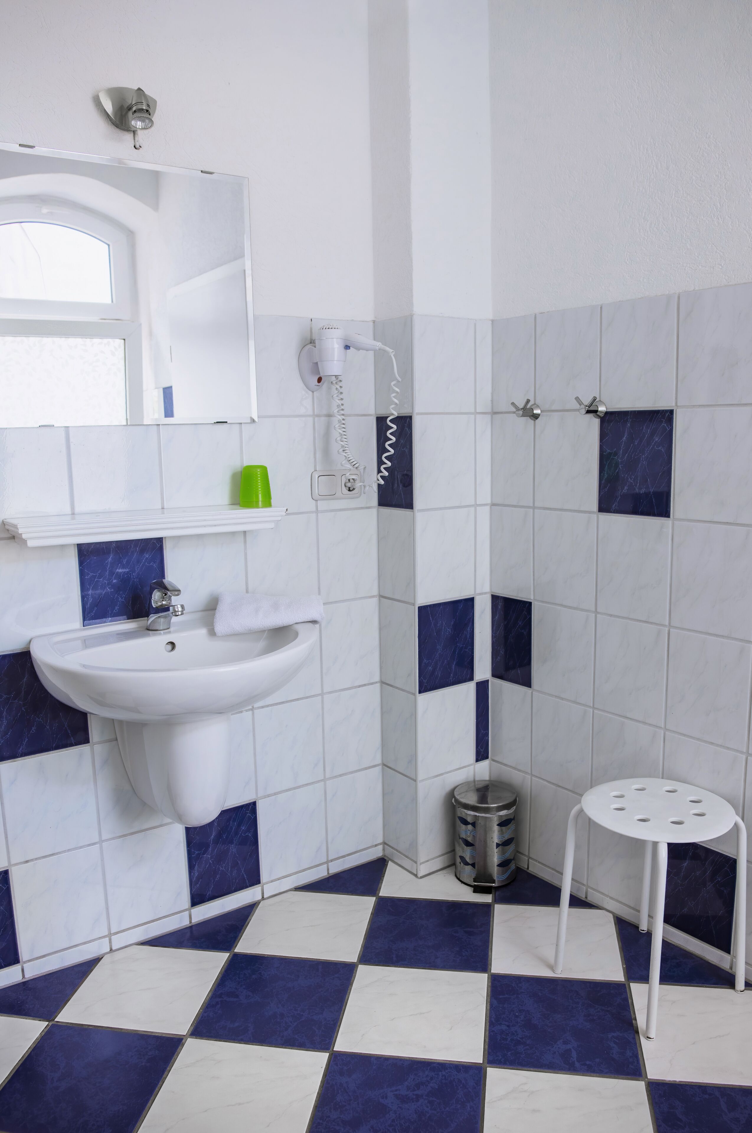 Ein Badezimmer mit Waschbecken, Spiegel und einer kleinen Hocker.
