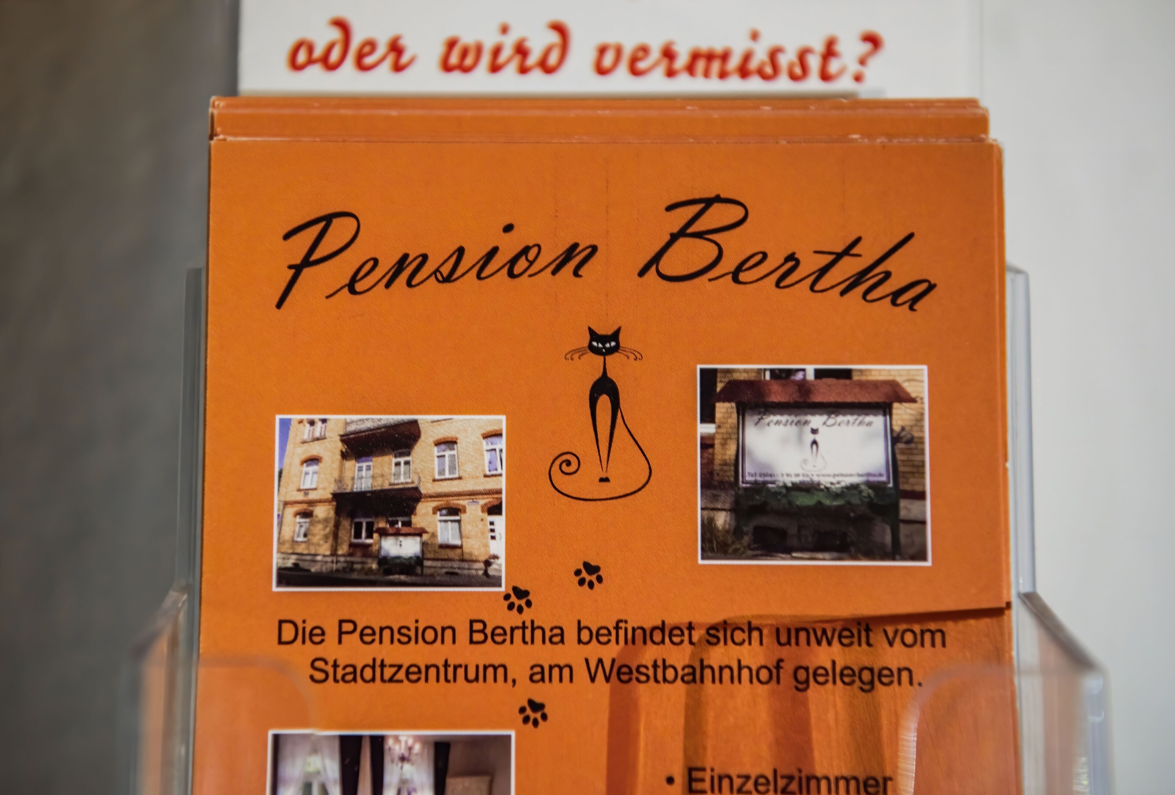 Caixa para o Pension Bertha com um logotipo de gato, indicando que é um estabelecimento que aceita animais de estimação. Localizada fora do centro da cidade, perto da estação Westbahnhof.