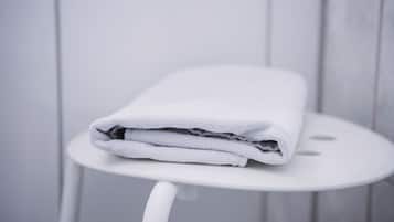 A white towel folded on a white stool in a bathroom with white tiles.
