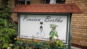 A sign for Pension Bertha with a cat illustration, contact number, and website URL. - Pension Bertha (Jena)