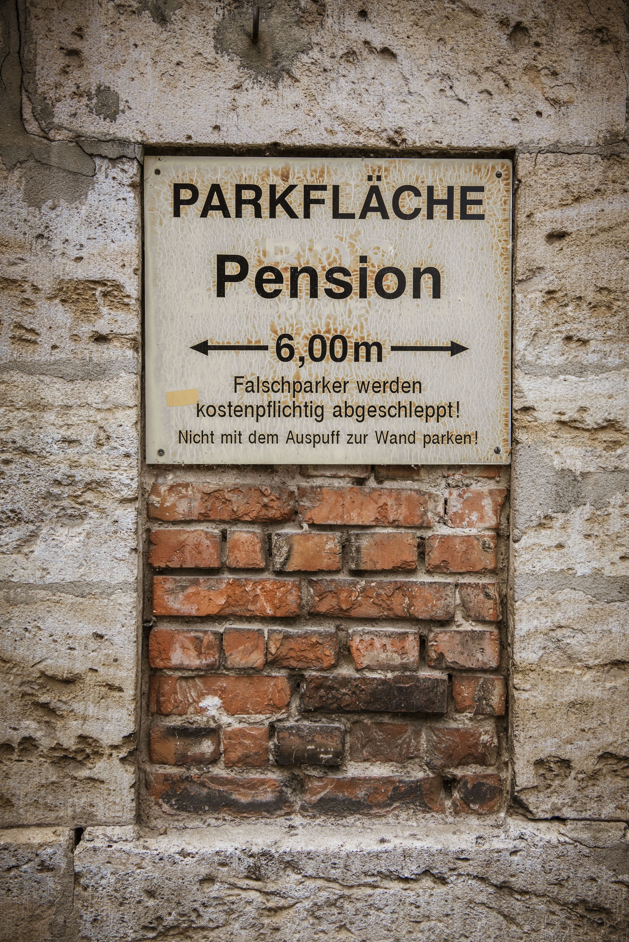 Ein Schild mit dem Text 'PARKFLÄCHE Pension' und einem nach rechts zeigenden Pfeil, der eine Richtung weist.