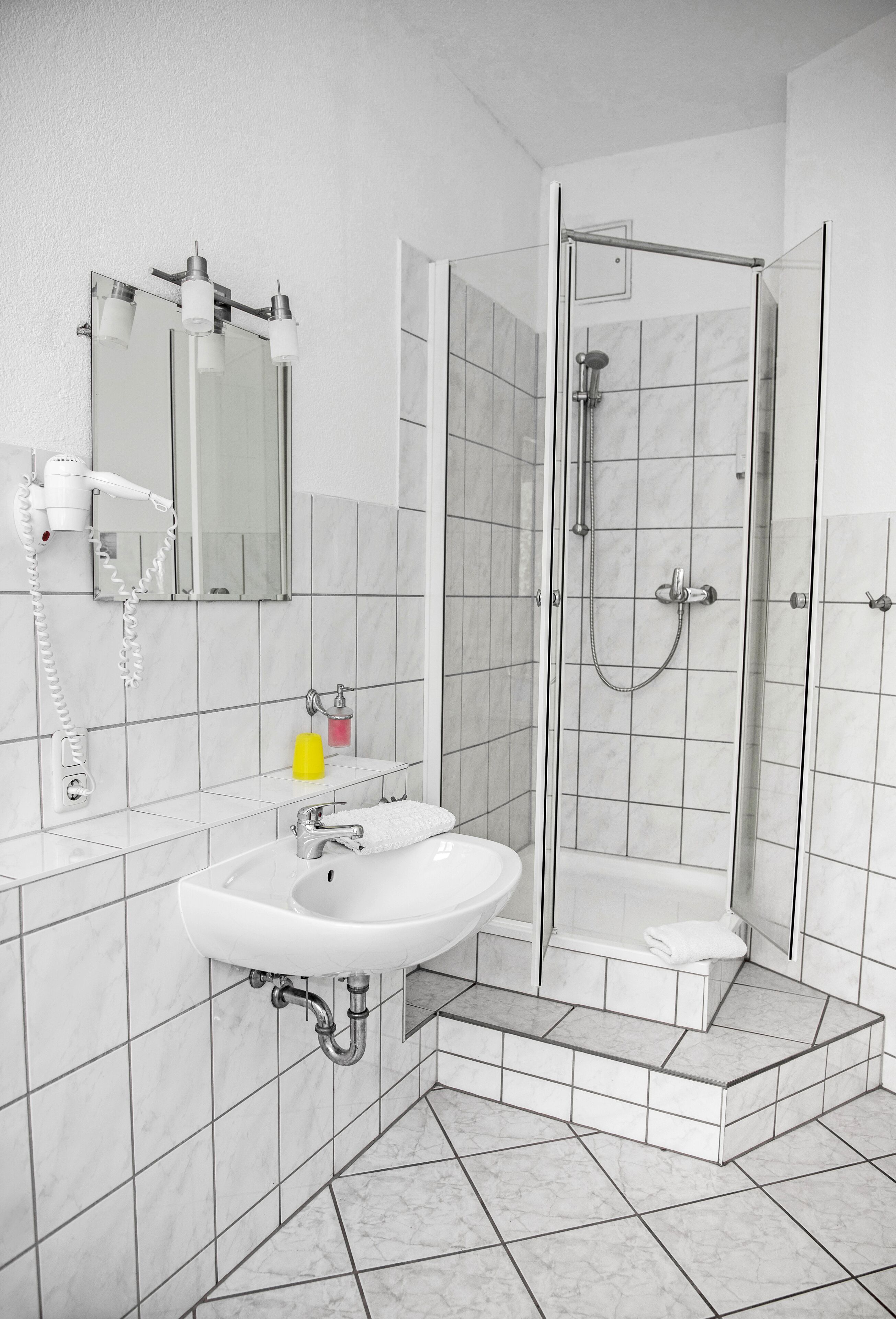 A modern bathroom with a white sink, mirror, and glass-enclosed shower.