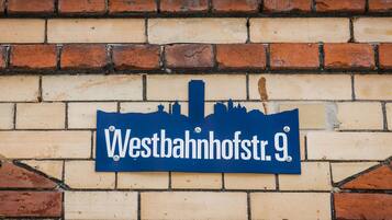 A street sign with the text "Westbahnhofstr. 9" mounted on a brick wall.