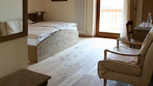 A room with a bed, a chair, a table, a window, and a door leading to an outdoor area. - Maso Fiorini (Isera)